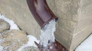 A brown pipe with ice coming out of it.