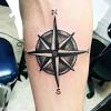 An anchor overlaid with a compass is illustrated over a red background on the wearer's forearm in this tattoo. 3