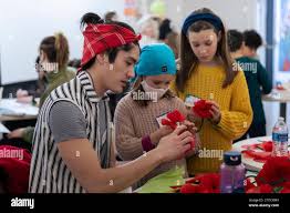 Seattle, Washington, USA. 17th December, 2023. Nick Woo (left) helps  attendees assemble paper flowers at a Portraits for Palestine event at the  Rainier Arts Cente. Jewish Voice for Peace organized the event