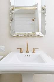 white pedestal sink with brushed gold