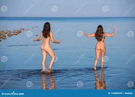 Dos Mujeres Desnudas Jovenes Que Se Relajan Y Que Juegan En La Playa Imagen  de archivo 