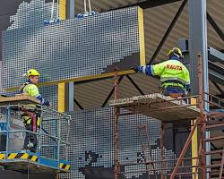 construction workers installing sandwich panels on a building facade resmi