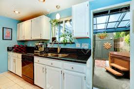 The refrigerator and freezer are hidden behind cabinetry designed to look like a large armoire. Light Blue Kitchen Room With White Cabinets And Black Counter Top Kitchen Room Has Exit To Backyard With Jacuzzi Stock Photo Picture And Royalty Free Image Image 34826108