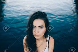 The long bangs and subtle highlights over dark brown hair add to the charm of this cute haircut. Portrait Of Cute Girl With Long Dark Hair Big Eyebrows And Blue Stock Photo Picture And Royalty Free Image Image 105828470