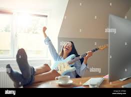 Wunderschöne Frau mit Gitarre vor Freude schreien, während nackte Socke  Füße auf Schreibtisch neben Computer sind Stockfotografie - Alamy