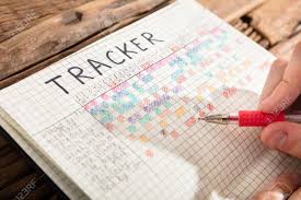 Close Up Of A Persons Hand Drawing Tracker Chart On Grid Notebook