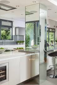 A Highly Contemporary Crisp Handleless Gloss Lacquered White Kitchen With Matt Grey Accents Corian Kitchen Mirror Kitchen Decor Trends Interior Design Kitchen