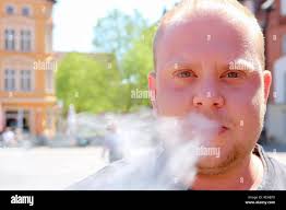 A young man with a beard smoking electronic cigarette Stock Photo