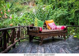 Patio furniture allows you to comfortably spend countless hours outside with family and friends. Outside Patio Outdoor Patio Furniture With Multi Color Pillows On Hardwood With Lush Foliage Background Canstock