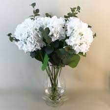 The vigorously growing hydrangea shrub symbolizes growth, heartfelt emotions, and prosperity. Elegant White Hydrangeas Vase Artificial Flower Arrangements