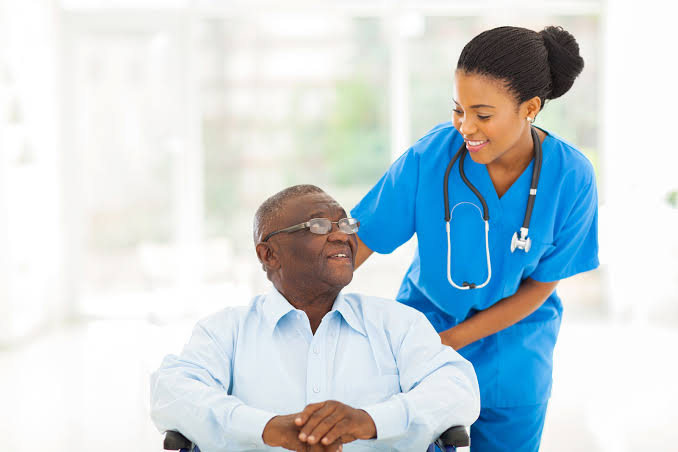 Healthcare professional speaking with an elderly patient in a wheelchair