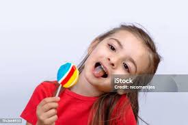 Little Laughing Girl Holding Candy Stock Photo