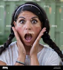 A surprised woman holds her face in alarm Stock Photo