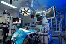 A hospital room with a patient on a table and a doctor standing behind him The room is brightly lit and has several monitors and medical equipment | Premium Photo