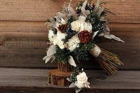 A rustic winter wedding centerpiece of a wood slice, moss, a tree stump and a candle in a candleholder wrapped with twine. Rustic Winter White Wedding Bouquet And Grooms Boutonniere Etsy White Winter Wedding Winter Wedding Bouquet Wedding Bouquets
