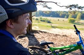 A man in a helmet looking at a bike. Man human face, people.