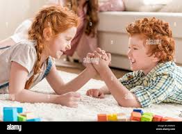 side view of brother and sister playing arm wrestling, family fun at home  concept Stock Photo - Alamy