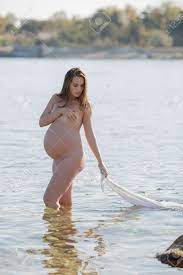 Expectant Mother Bathes In Sea. Naked Pregnant Woman Walks Knee-deep In  Water And Pulling With Her Wet White Sarong Stock Photo, Picture and  Royalty Free Image. Image 159849221.