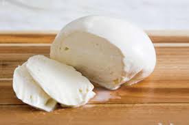 Close-up of blue cheese aging on racks, handled by a person wearing gloves in an industrial setting.