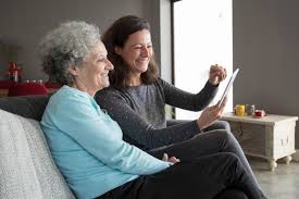 Happy elderly woman and her daughter browsing on tablet computer ...