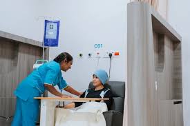Nurse attending a patient in a recliner during outpatient chemotherapy with IV pole and treatment bay