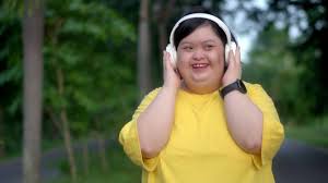 Down syndrome girl exercising in the park wearing headphones.