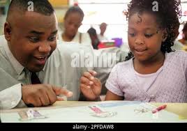 Art teacher Al Harris, left, looks over 4th grader Kiara Goode's work at  Ingleside Elementary School