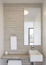 A white door opens to a beautiful transitional powder room featuring a wall covered in mushroom colored grasscloth and trimmed with white baseboards accented by an oval window framed in white sitting above a round brass accent table on diamond patterned black marble floors illuminated by a glass chandelier. 26 Best Modern Powder Rooms Ideas In 2021 Modern Powder Rooms Bathroom Decor Bathroom Design
