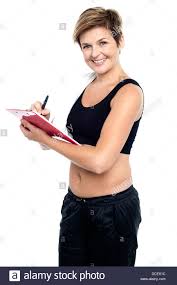 Female Gym Instructor Writing Diet Chart For Trainees All