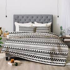 The home decor consists of multicolor geometric shapes and animals against a white, wooden texture. Black And White Aztec Pattern Comforter Allyson Johnson