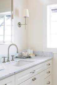 Bathroom sconces and outlets are mounted onto a large mirror in modern bathroom. Satin Nickel Bathroom Sconces And Faucet Transitional Bathroom