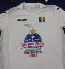 A estrela dourada sobre o escudo representa a copa libertadores da américa conquistada pelo clube em 2004. Once Caldas Specialnaya Futbolka 2014
