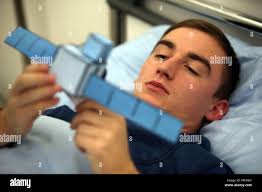Lucas Braunschmidt, a test person of the long-term bed rest study of the  German Aerospace Center, looks at a model of the space probe Rosetta as he  lies in a bed in
