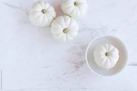 Selective focus, copy space, top view. White Pumpkins On White Background By Nadine Greeff
