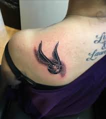 There, on the small patch of skin showing, was the corner of what could possibly be a black tattoo. A Golden Snitch Tattoo From Harry Potter Chapter On Back Shoulder Blurmark