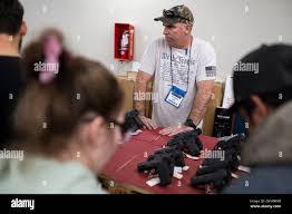 Kirby Huffman, center, assists customers as they look at pistols for sale  during the first day of the Silver Spur Gun and Blade Show Saturday, Jan.  22, 2022 in Odessa, Texas. (Eli