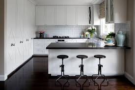 A clean white countertop and glossy brown cabinetry, paired with simple brown backed barstools give a modern feel to this kitchen. 9 Kitchen Peninsula Ideas Housessive