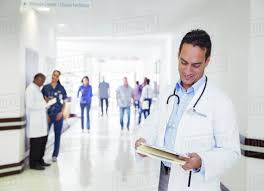 doctor reading medical chart in hospital hallway stock photo