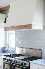 White kitchen with wood range hood. White Range Hood With Barnwood Trim Molding