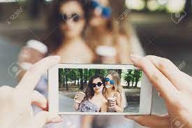 コーヒーと 2 つの女の子の友達を奪う屋外と誰かハメ撮りビュー スマート フォンのデジタル  カメラで写真を撮るします。夏の公園で楽しい携帯電話の画面で若い女性。ライフ スタイルの肖像画。の写真素材・画像素材 Image 62161088