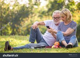 Happy Senior Couple Relaxing In Park Using Smartphone Together Old People Sitting On Grass In The Summer Park Looking Couples People Sitting Best Photo Poses
