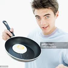 Teenage Boy With A Fried Egg In A Frying Pan High-Res Stock Photo