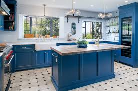 A single long kitchen counter with a subway tile backsplash, open shelving, and a kitchen island painted a corresponding blue. Blue Kitchen Ideas Cabinets Walls And Counters