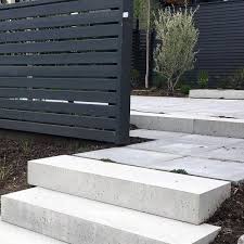 Japanese ornamental grasses and other shrubs are side by side with dark boulders as they make way for the rugged stone garden steps. 60 Concrete Patio Ideas Unique Backyard Retreats