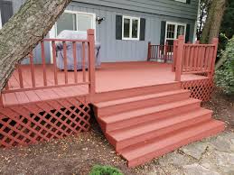Red brick house, with deck with white railings and composite decking. Tips For Applying Solid Deck Stain Dengarden