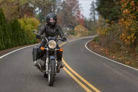 Female Biker Riding Motorcycle On Country Road Stockphoto