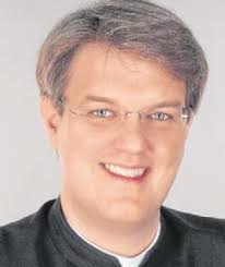 Der Neupriester kniet vor dem Bischof