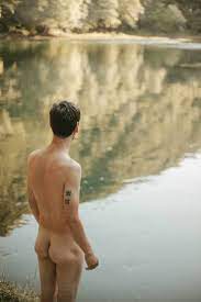 Back view of naked man standing by the river stock photo