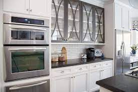 Glass cabinet doors with blue interior, white trim and butter yellow walls. How To Style The Glass Cabinet Doors In Your Kitchen Designed