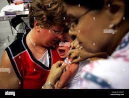 Aug 07, 2004; San Antonio, TX, USA; Garrett Chase, 6, of Castroville, is  consoled by his mother Denea Chase as LVC (Licensed Vocational Nurse)  Sheila Folshinsky administers an immunization. The Metropolitan Health